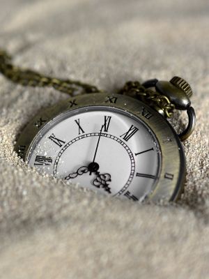 a pocket watch partially buried in sand