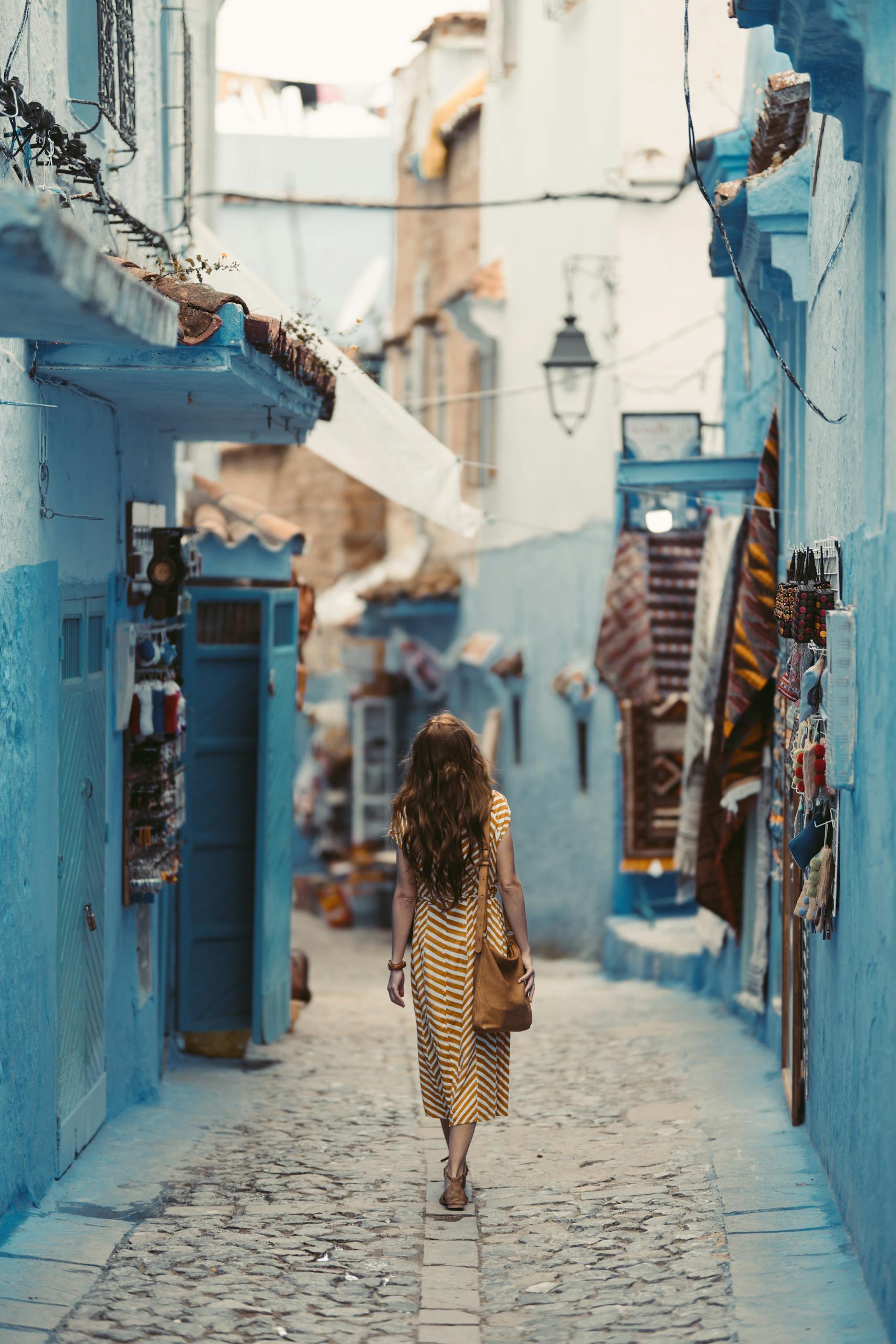 A woman wanders through the vibrant blue alleyways of Chefchaouen, Morocco.