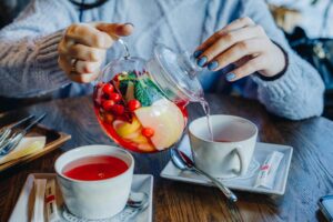 woman sitting at a table pouring her herbal tea into her tea cup